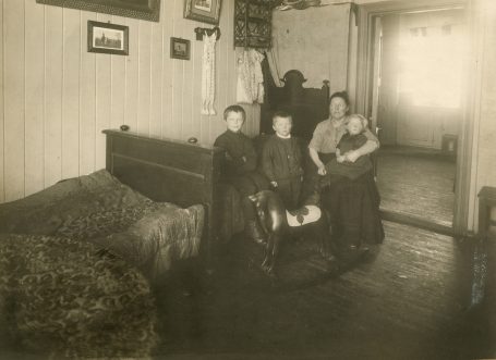 Mor med tre barn fotografert i oppholdsrom i leilighet i Stavangergaten. Foto: Ukjent fotograf / Norsk Teknisk Museum